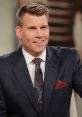 Scott Hanson smiles confidently in a tailored suit, showcasing a stylish tie and pocket square during a presentation.