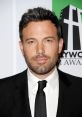 Ben Affleck in a black suit with a tie, showcasing his stylish look at a Hollywood film awards event.