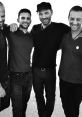 Four friends posing together in casual attire, showcasing camaraderie and joy with a stylish black-and-white backdrop.