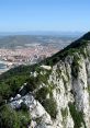 Panoramic view of Gibraltar's cliffs, showcasing the lush greenery and urban landscape under a clear blue sky.