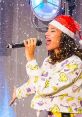 Singer in a festive Santa hat performs joyfully on stage during the Borrelshow, with snowflakes falling around her.