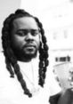 Arsonal Da Rebel in a stylish pose, showcasing his signature braids and casual attire, exuding a confident vibe.