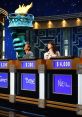 Contestants on stage during a "Jeopardy!" episode, featuring the iconic torch symbol and scoreboard with scores displayed.