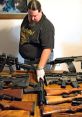 Gun owner inspecting a variety of firearms on a table, showcasing responsible firearm ownership and collection.