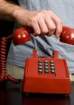 Hand holding a red retro phone, ready to hang up the phone after a conversation, showcasing nostalgic communication.