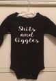 Black baby onesie with "Shits and Giggles" printed in white, perfect for playful and humorous baby outfits.