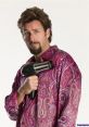 Character from Zohan holding a hairdryer, dressed in a vibrant paisley shirt, showcasing a comedic expression.