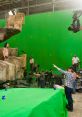 Behind-the-scenes of special effects production with green screen, actors, and crew setting up a scene.