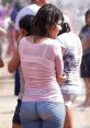 Young woman in a wet pink top and jeans enjoying a summer day at a water park, surrounded by friends and splashes.