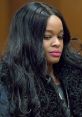 Close-up of a woman with long, wavy hair and vibrant lipstick, exuding confidence in a courtroom setting.