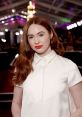 Karen Gillan showcases elegant fashion with red lips at a glamorous event, featuring soft waves and a chic white outfit.