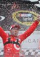 Celebrating victory, a jubilant NASCAR racer in a red suit sprays champagne, embodying the excitement of motorsports triumph.