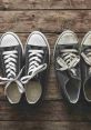 New black sneakers alongside worn-out shoes on a rustic wooden surface, showcasing the contrast between old and new footwear.