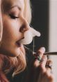 Woman with pink hair exhaling smoke while holding a smoking device, capturing a relaxed vibe and artistic expression.