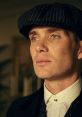 Close-up portrait of a character in Peaky Blinders, showcasing a sharp suit, iconic cap, and intense gaze.