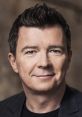 Rick Astley smiling in a casual black jacket, showcasing his iconic look and charm for fans and music lovers.