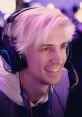 xQcOW playing games with headphones, showcasing his signature white hair and vibrant gaming setup at a live event.