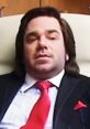 Matt Berry as Douglas Reynholm in I.T. Crowd, showcasing his iconic suit and cheeky expression in the office setting.