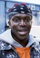 KSI laughing enthusiastically, wearing a bandana and casual clothing, showcasing his vibrant personality.