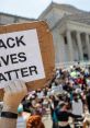 Protester holding a sign reading "Black Lives Matter" at a rally, advocating for racial justice and equality.