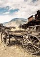 Rustic wooden wagon in an abandoned Wild West town, surrounded by mountainous scenery and dusty trails under a cloudy sky.