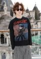 Eboy fashion: stylish guy in sunglasses, Gorillaz tee, and striped pants, set against a unique architectural backdrop.