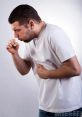 Young man experiencing coughing and wheezing, holding his stomach in discomfort against a neutral background.