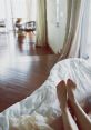 Relaxing bedroom scene featuring bare feet on a bed, with natural light illuminating a modern, stylish interior.