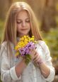 Girl gently holding a bouquet of vibrant wildflowers, radiating tranquility and connection to nature in a serene outdoor setting.