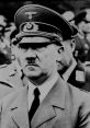 Portrait of Adolf Hitler in military uniform, capturing his stern expression during a public event. Historical significance noted.