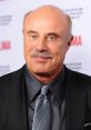 Dr. Phil McGraw smiling confidently in a formal suit, promoting his latest mental health initiatives and television show.