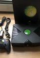 Original Xbox console with controller and cables, showcasing classic gaming setup for enthusiasts and collectors.