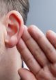 Close-up of a man's ear, with a hand cupping it, illustrating the act of listening intently for sound.