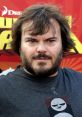 Jack Black with tousled hair and beard, wearing a graphic T-shirt at a vibrant event backdrop, exuding charisma and humor.