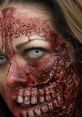 Close-up of a zombie face with intense makeup, showcasing bloody wounds and a chilling expression, perfect for horror themes.