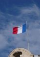 French flag flying against a blue sky, symbolizing national pride and identity in France.