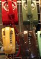 Colorful retro telephones hanging on a rack, featuring red, green, yellow, and brown designs with coiled cords.