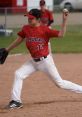 Young baseball pitcher in red jersey throws a fastball during a 15U AAA game, showcasing skill and athleticism.