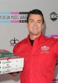 Papa John holding pizza boxes, smiling at the American Music Awards, promoting the brand with enthusiasm and energy.