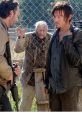 Rick and Daryl face a zombie threat behind a fence in a tense moment from The Walking Dead, highlighting survival challenges.