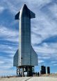 SpaceX Starship towering against a blue sky, showcasing its sleek design during a test launch phase at the facility.