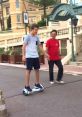 Young man riding a hoverboard on a street while an adult walks beside him, enjoying a sunny day outdoors.