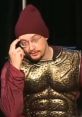 Sam Hyde performing in a gold costume and maroon beanie, showcasing his unique comedic style on stage.