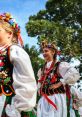 Young girls in traditional Polish costumes celebrate with floral crowns, showcasing vibrant culture and joyful expression.