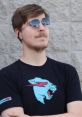 Person wearing sunglasses and a black t-shirt with a blue lion design, posing confidently outdoors.