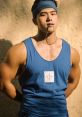 Muscular man in a blue tank top, wearing a headband, poses confidently against a textured background.