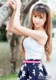 Stylish young woman in a floral skirt and white top, posing gracefully by a tree, showcasing a casual, vibrant look.