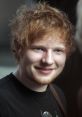 Smiling Ed Sheeran with tousled hair, wearing a black t-shirt, showcasing his approachable persona.