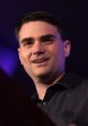 Ben Shapiro speaking at an event, engaging the audience with a confident smile and passionate expression.