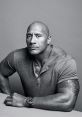 Dwayne Johnson in a stylish gray shirt, showcasing his iconic muscular build and tattoo, exuding confidence and charisma.